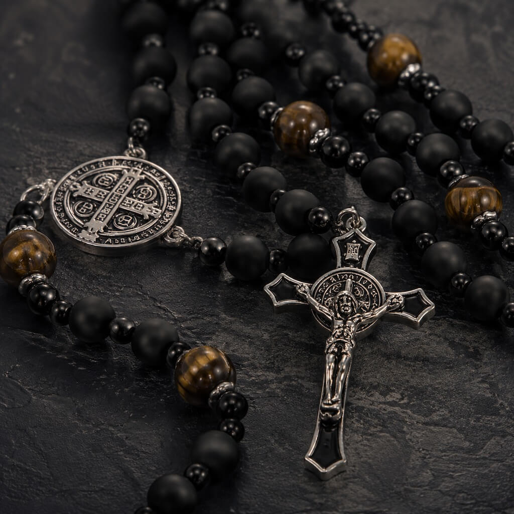 Close-up of the black enamel St. Benedict crucifix with silver-tone details and matte black rosary beads.