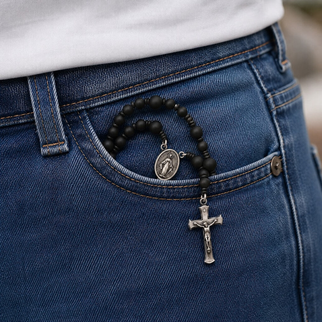 Black Compact Everyday Rosary placed in a standard jeans front pocket for discreet daily carry.