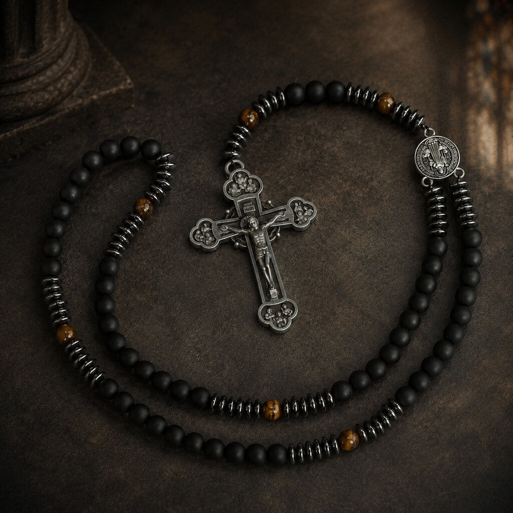 Top-down view of the Heritage St. Benedict rosary with black beads, tiger eye accents, medal, and crucifix in a church-inspired setting.