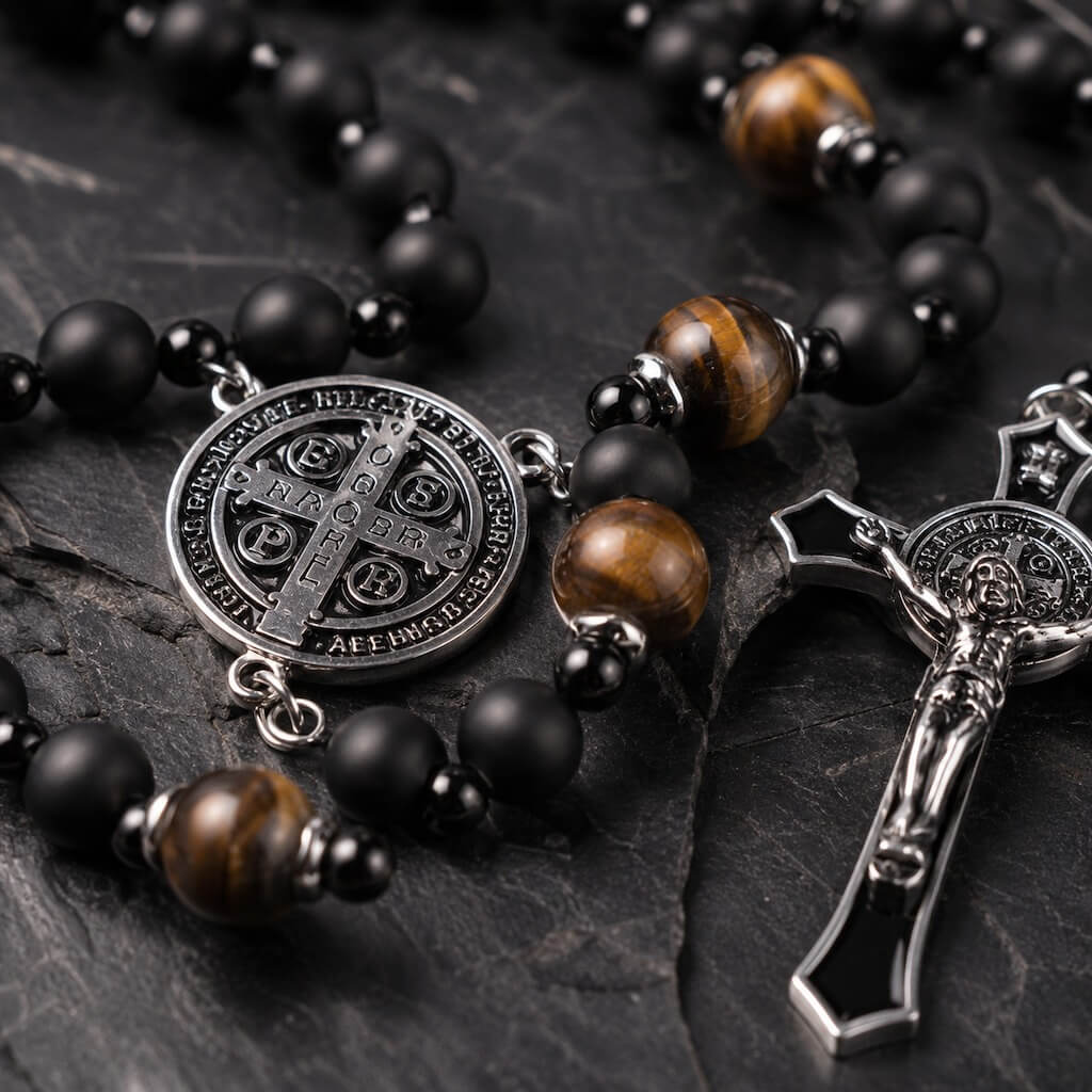 Close-up of matte black onyx Hail Mary beads and polished brown tiger eye Our Father beads on the St. Benedict rosary.