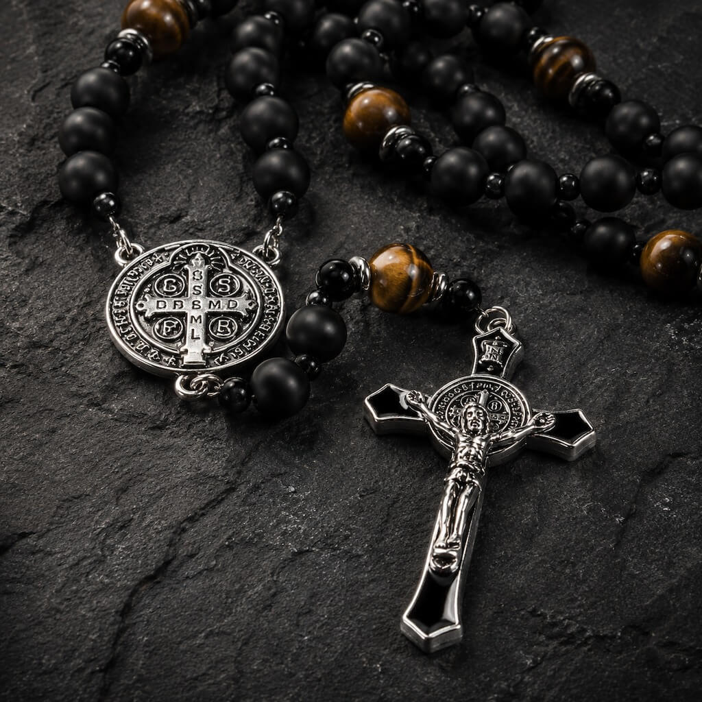 Detailed view of the St. Benedict medal, tiger eye beads, and black enamel crucifix on the natural stone rosary.