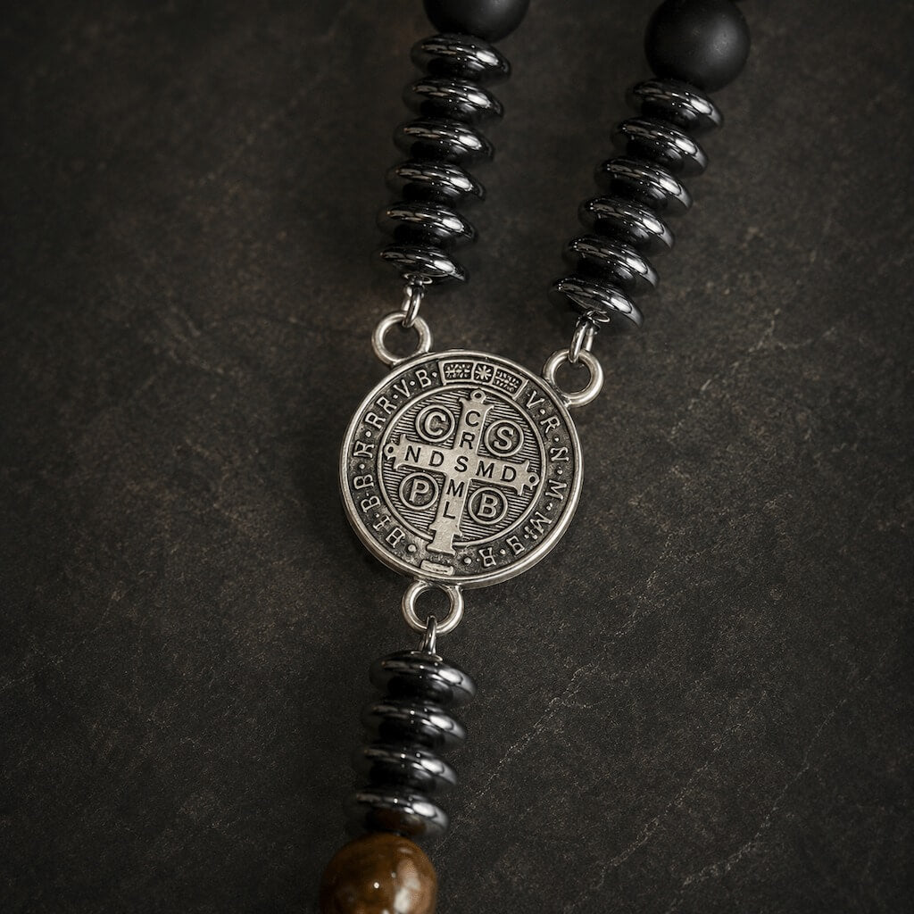 Close-up of the reverse side of the antiqued St. Benedict medal with an engraved cross and traditional devotional lettering.