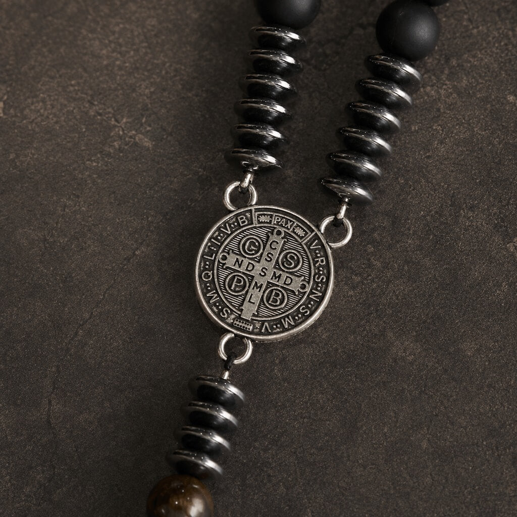 Macro view of the St. Benedict medal reverse showing the central cross, devotional initials, and antiqued silver-tone finish.