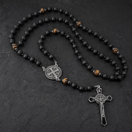St. Benedict five-decade rosary with matte black onyx beads, tiger eye accents, a silver-tone medal, and a black enamel crucifix on dark stone.