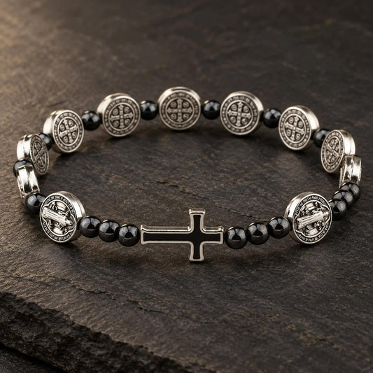 St. Benedict hematite bracelet with silver-tone medals and black cross displayed on dark stone